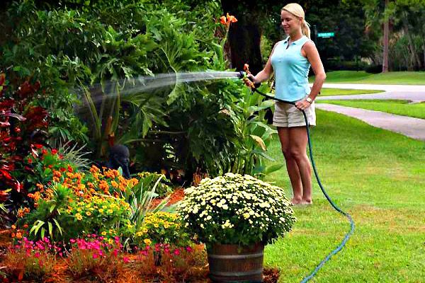 fille arrosant le jardin avec des tuyaux